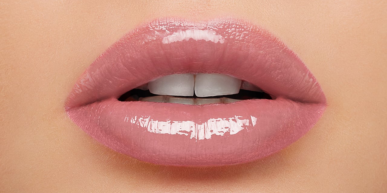 Close up of a classic light nude pink lip gloss worn on lips